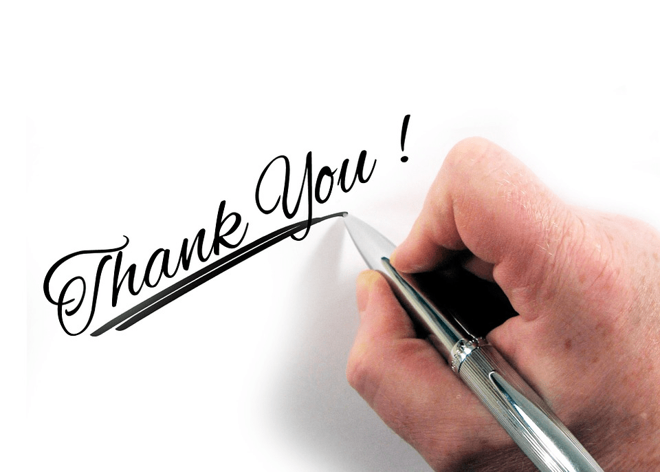 A hand writing "thank you" with a ballpoint pen